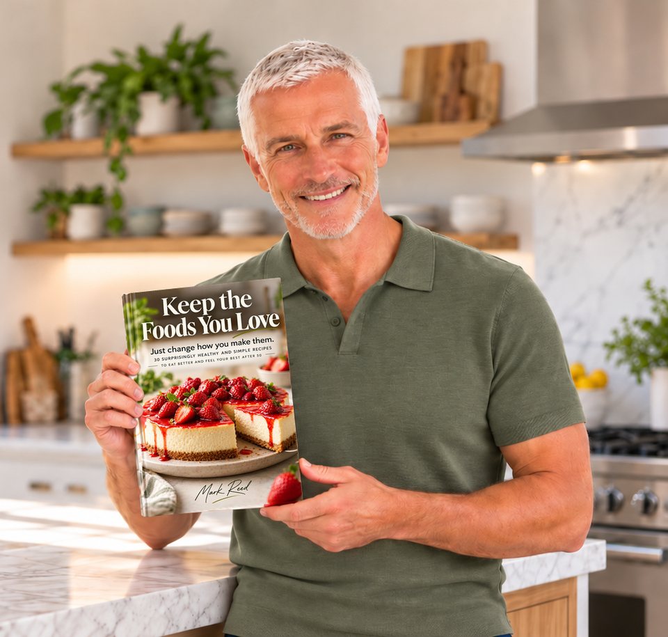 Mark Reed in a kitchen holding the book Keep the Foods You Love.